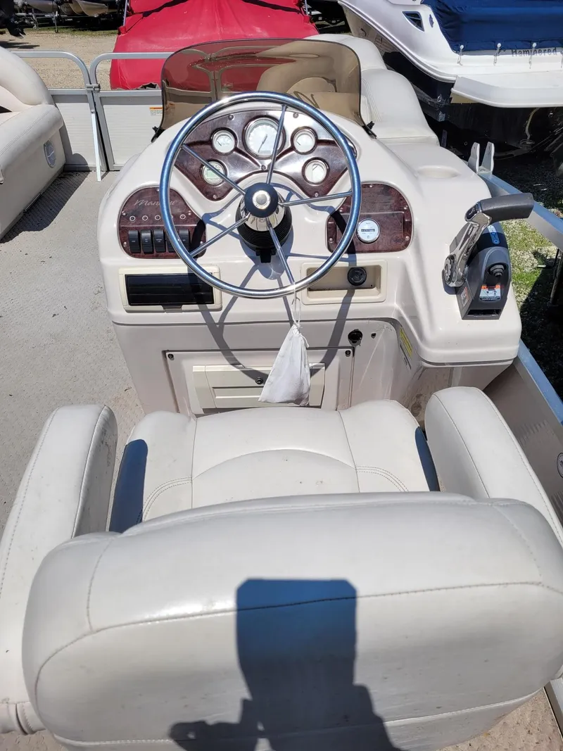 Slide: The Image of 2008 Manitou 20 Oasis boat dashboard and steering wheel with white captain's chair. - 9