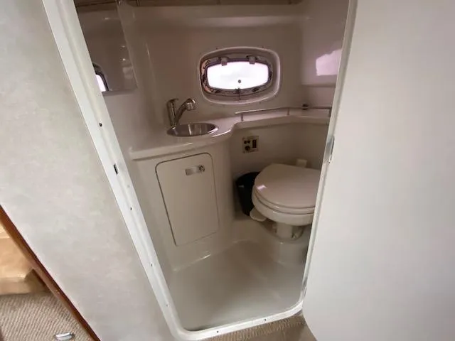 Slide: The Image of Compact bathroom in 2011 Sea Ray 280 Sundancer boat with sink, toilet, and porthole window. - 21