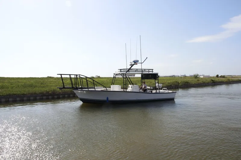 Slide: The Image of 1997 Custom 31 Center Console boat on calm water near grassy shore. - 45
