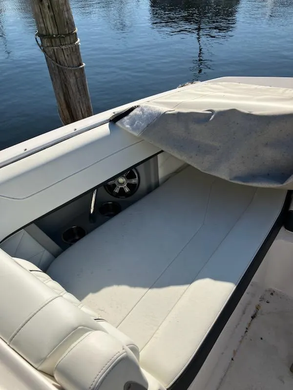 Slide: The Image of 2020 Regal 26 OBX boat with white seating and cover by the water. - 16