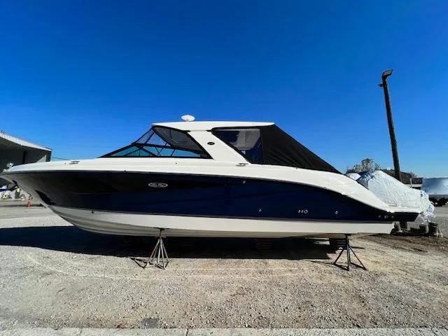 The Image of 2024 Sea Ray SLX 400 OB boat on stands under clear blue sky. - 0