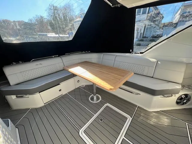 Slide: The Image of 2024 Sea Ray SLX 400 OB boat interior with cushioned seating and wooden table. - 23