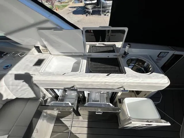 Slide: The Image of 2024 Sea Ray SLX 400 OB boat kitchen with sink, grill, and storage drawers. - 25