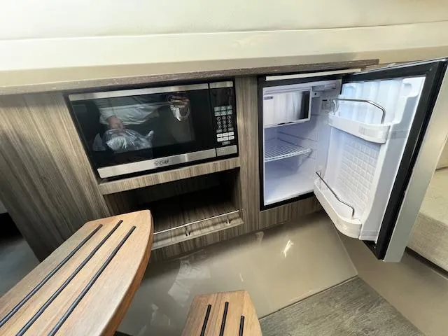 Slide: The Image of 2024 Sea Ray SLX 400 OB galley with microwave and open refrigerator. - 8