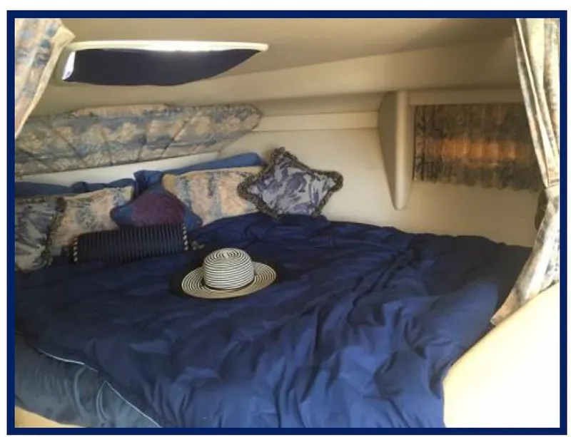 Slide: The Image of Cozy cabin interior of a 2000 Formula 31 PC boat with blue bedding and decorative pillows. - 18