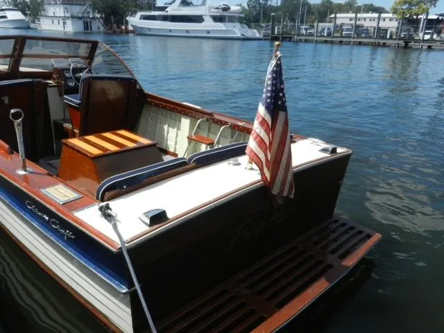 Slide: The Image of 1963 Chris-Craft Sportsman boat docked, American flag, luxury yachts in background. - 10