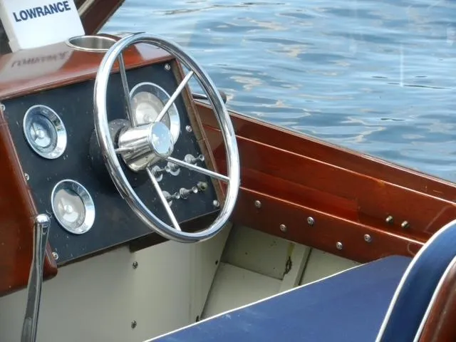 Slide: The Image of 1963 Chris-Craft Sportsman boat dashboard with steering wheel and gauges on water. - 16