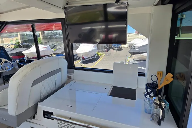 Slide: The Image of 2024 Regal 36 XO yacht interior with helm, seating, and kitchenette area. - 28