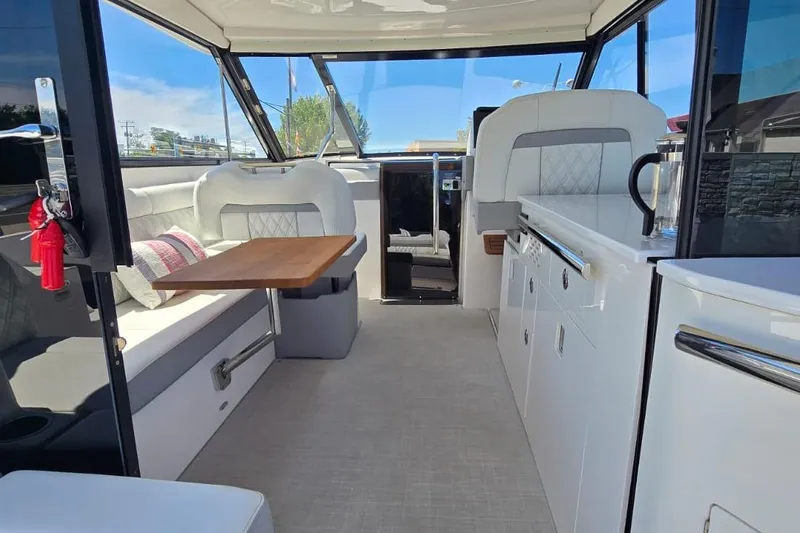 Slide: The Image of 2024 Regal 36 XO yacht interior with modern seating, table, and kitchenette. - 32