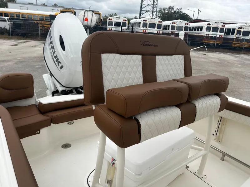 Slide: The Image of 2024 Pioneer 202 Islander boat interior with brown and white cushioned seating, Suzuki outboard motor. - 10