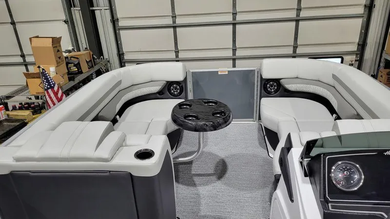Slide: The Image of 2024 Hurricane Fundeck 2360 SBC OB interior with seating and table in a garage. - 9