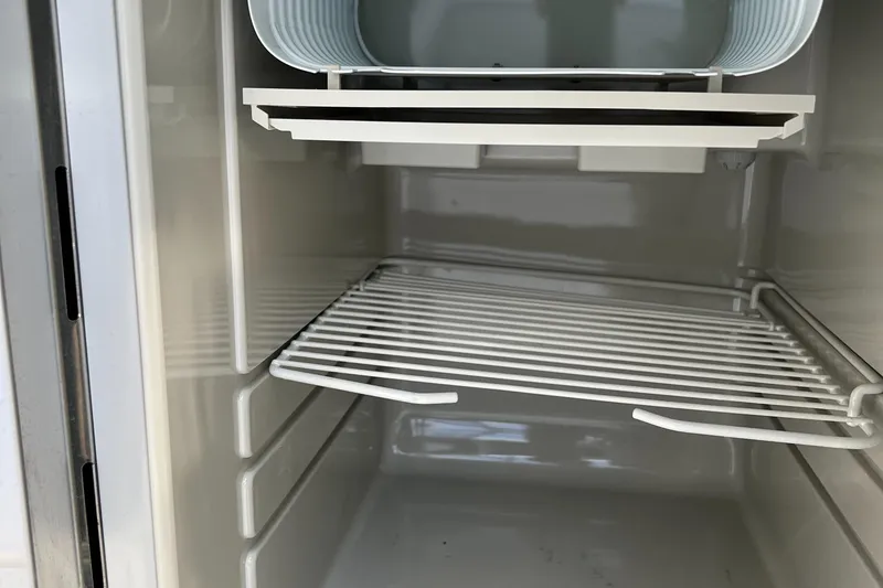 Slide: The Image of 2015 Hunt Yachts Harrier Sport refrigerator interior with wire shelf and storage compartment. - 11