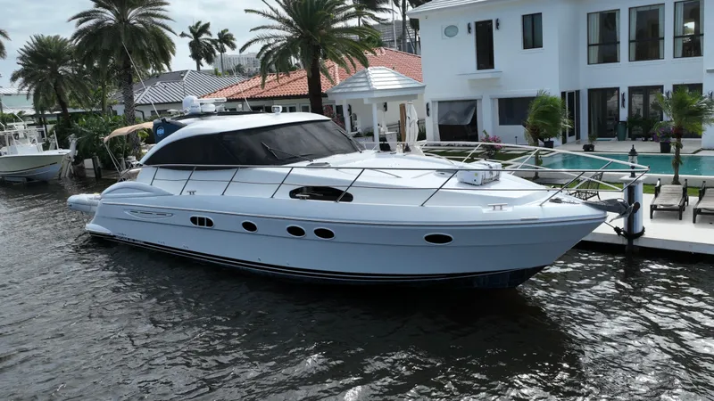 Slide: The Image of 2006 Neptunus 55 Cabrio yacht docked by a luxurious waterfront property. - 1