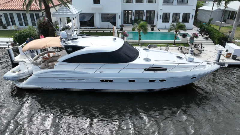 Slide: The Image of 2006 Neptunus 55 Cabrio yacht docked by a luxurious waterfront property. - 2