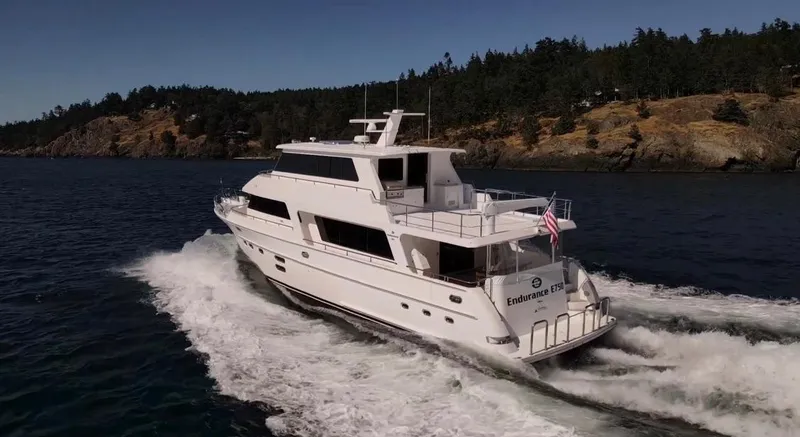 Slide: The Image of 2025 Hampton 750 Endurance LRC yacht cruising on scenic waterway near forested shoreline. - 3