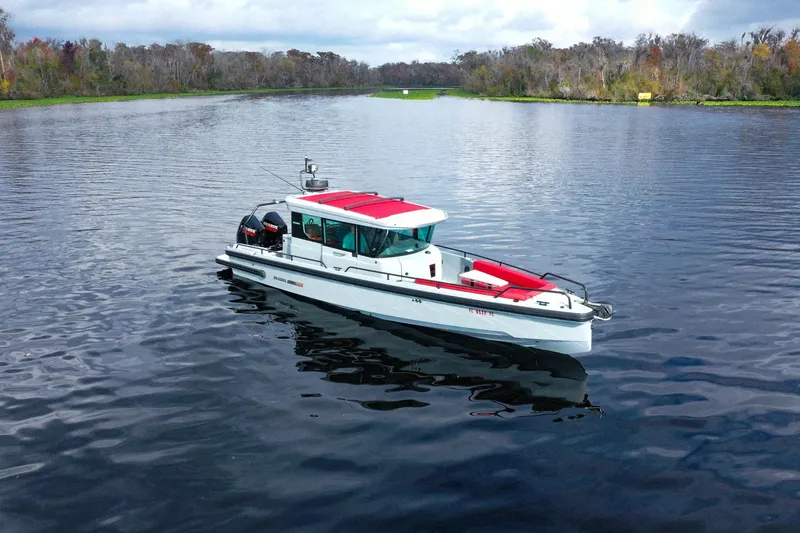 Slide: The Image of Ein Axopar Brabus Shadow 500 T-Top von 2022 fährt auf einem ruhigen Fluss mit bewaldeten Ufern. - 0