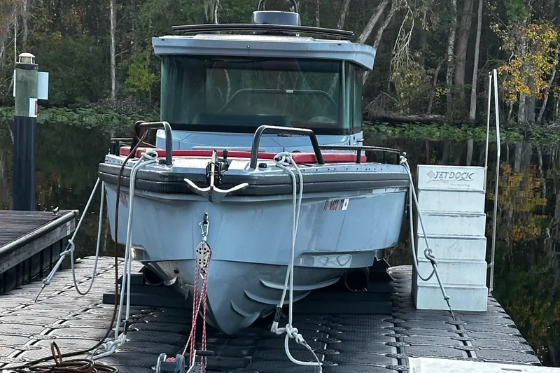 Slide: The Image of Ein Axopar Brabus Shadow 500 T-Top von 2022 liegt an einem Dock in einem bewaldeten Gebiet. - 27