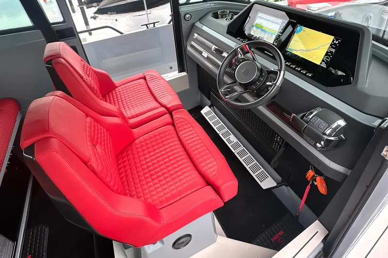 Slide: The Image of Das Bild zeigt den Innenraum eines Axopar Brabus Shadow 500 T-Top von 2022 mit roten Sitzen und modernen Instrumenten. - 11