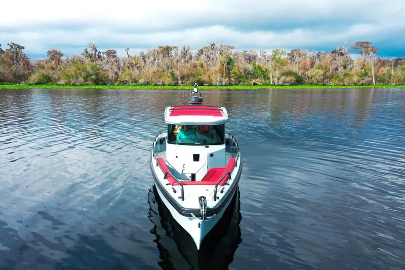 Slide: The Image of Ein Axopar Brabus Shadow 500 T-Top von 2022 fährt auf einem ruhigen Fluss mit bewaldetem Ufer. - 2