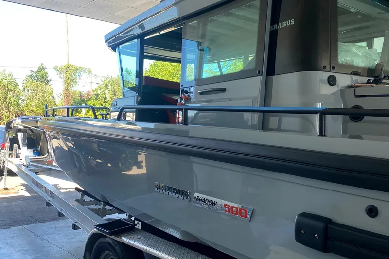 Slide: The Image of Ein Axopar Brabus Shadow 500 T-Top von 2022 steht auf einem Anhänger in einem überdachten Bereich. - 26