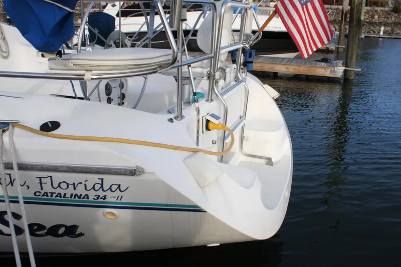 Slide: The Image of Stern view of a 1996 Catalina 34 MkII sailboat docked, featuring an American flag. - 10