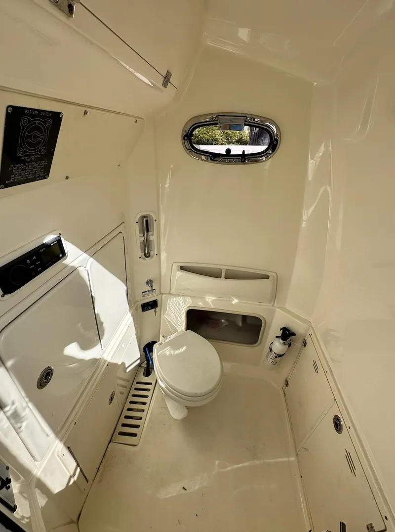 Slide: The Image of 2014 Boston Whaler 280 Outrage boat interior with toilet and storage compartments. - 18