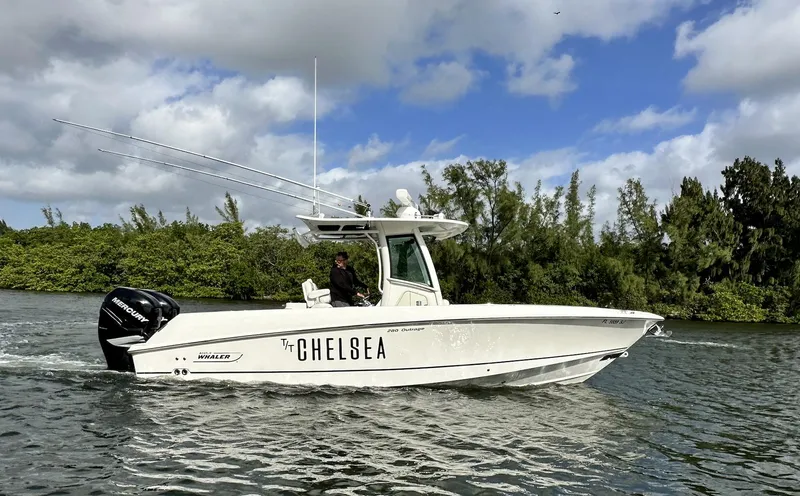 Slide: The Image of 2014 Boston Whaler 280 Outrage boat cruising on a river with lush greenery. - 5
