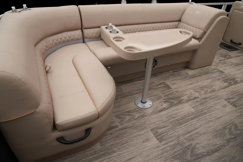 Slide: The Image of 2024 Ranger Reata 220C pontoon boat interior with beige seating and table. - 38
