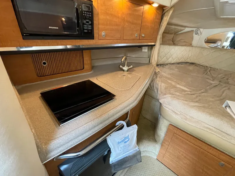 Slide: The Image of 2006 Sea Ray 290 Amberjack cabin with kitchenette and cozy sleeping area. - 25