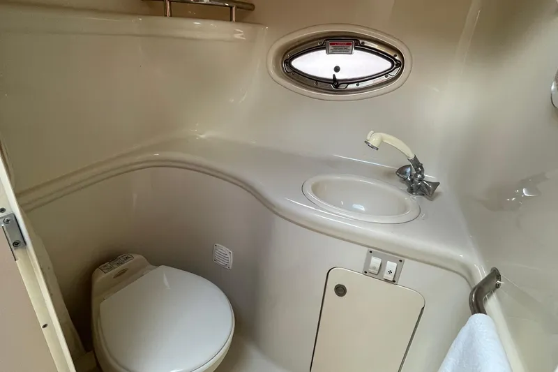 Slide: The Image of 2006 Sea Ray 290 Amberjack bathroom with toilet, sink, and porthole window. - 47