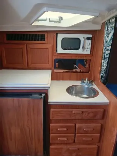Slide: The Image of 1995 Luhrs 32 Tournament Open galley with microwave, sink, and wooden cabinetry. - 9