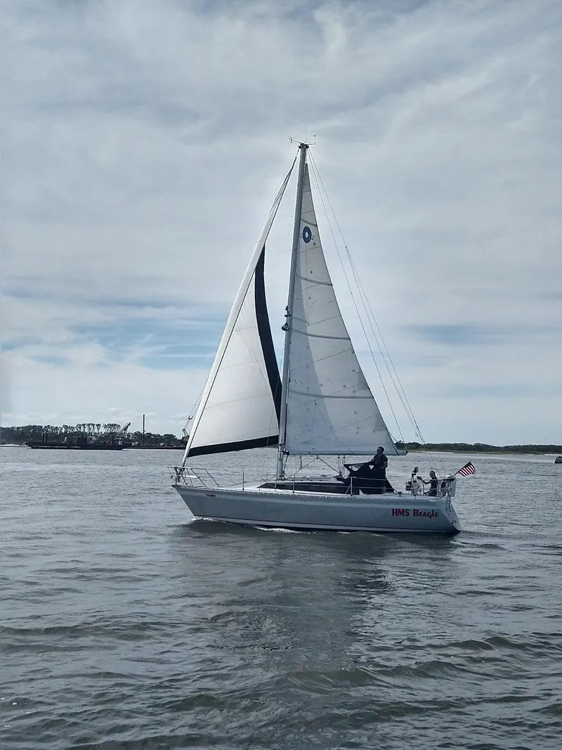 Slide: The Image of 1987 O'Day 322 sailboat cruising on a calm sea under a cloudy sky. - 12