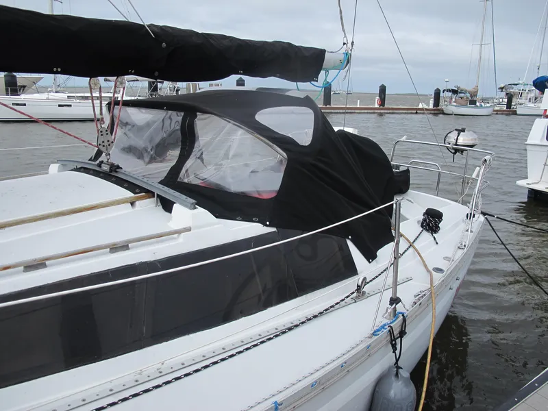 Slide: The Image of 1987 O'Day 322 sailboat docked at a marina, featuring a black canvas cover. - 7