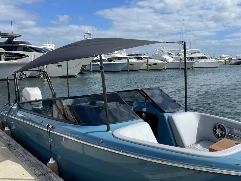 Slide: The Image of 2022 Cranchi 26 Rider boat docked at marina with canopy, surrounded by yachts. - 1