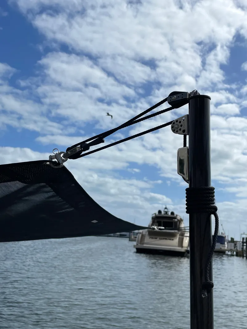 Slide: The Image of Cranchi 26 Rider 2022 boat docked under a cloudy sky with a sunshade. - 30