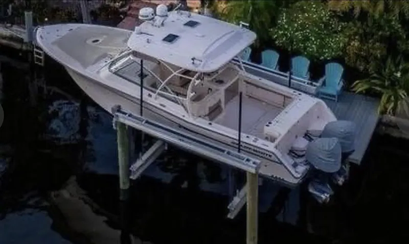 The Image of 2014 Grady-White Freedom 335 boat on lift, dockside with chairs and lush greenery. - 0