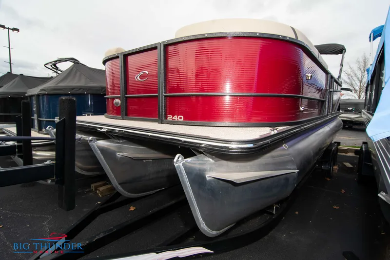 Slide: The Image of 2023 Crest Classic Platinum 240 SLC pontoon boat with red exterior, docked at marina. - 0