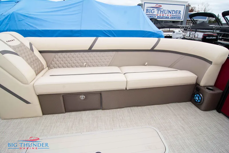 Slide: The Image of 2023 Crest Classic Platinum 240 SLC boat interior with beige seating and storage. - 10