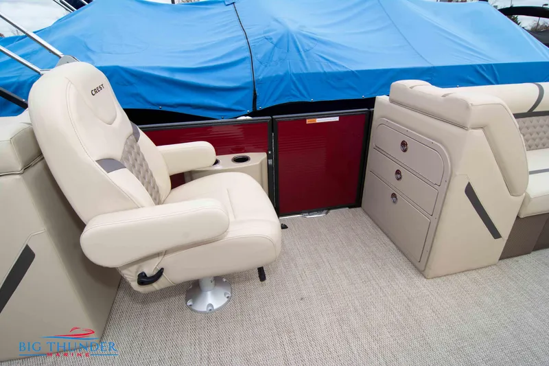 Slide: The Image of 2023 Crest Classic Platinum 240 SLC boat interior with beige captain's chair and storage compartments. - 35