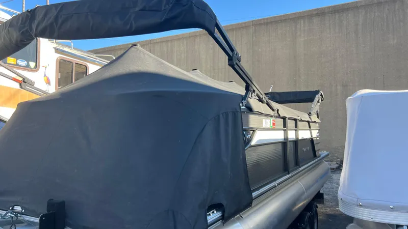 Slide: The Image of 2020 Crest Classic Platinum 220 SLC pontoon boat with black cover in storage. - 0