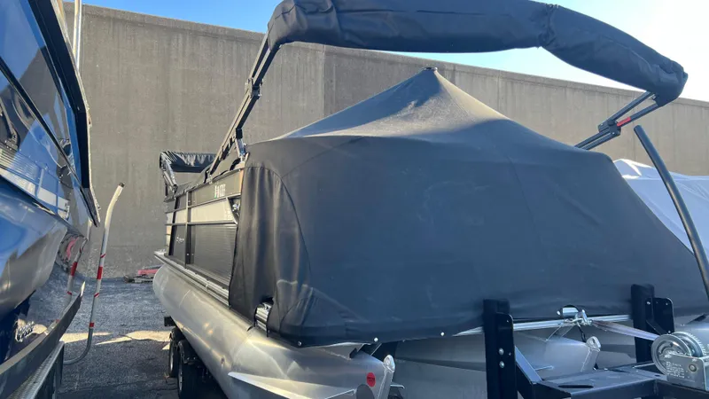 Slide: The Image of 2020 Crest Classic Platinum 220 SLC pontoon boat with black cover in storage. - 1