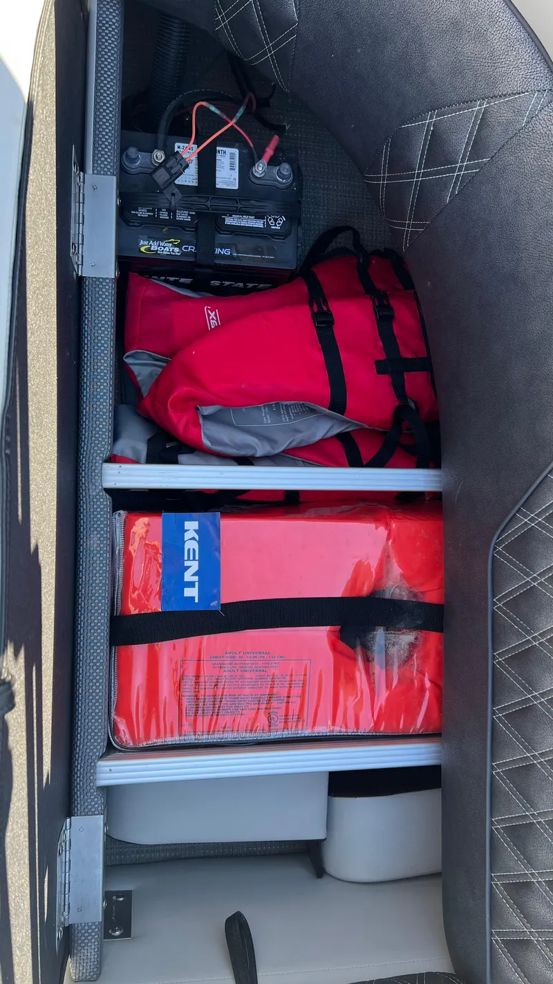 Slide: The Image of Storage compartment of a 2020 Crest Classic Platinum 220 SLC boat with battery and life jackets. - 14