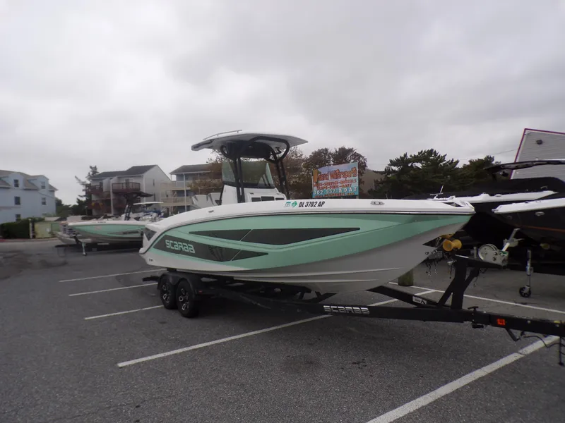 Slide: The Image of 2023 Scarab 255 Open ID boat on a trailer in a parking lot. - 2