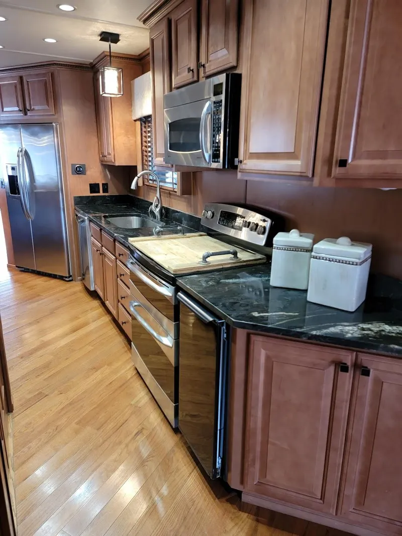 Slide: The Image of Modern kitchen in a 2008 Sumerset Houseboat with stainless steel appliances and wooden cabinets. - 12