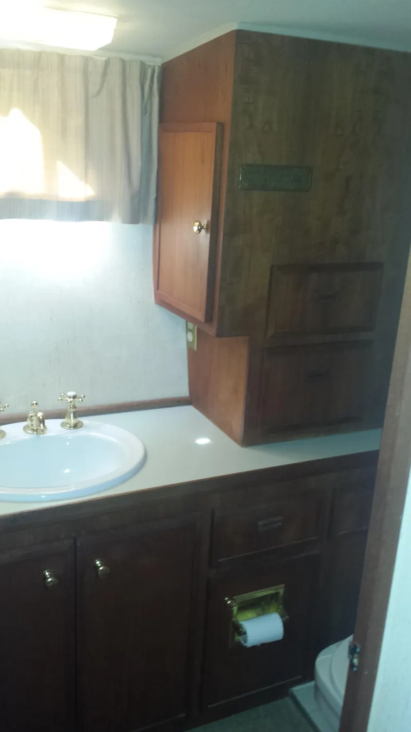 Slide: The Image of 1975 Uniflite Aft Cabin bathroom with wooden cabinets and sink. - 26