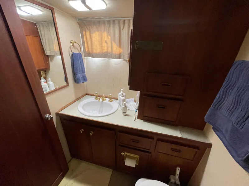 Slide: The Image of 1975 Uniflite Aft Cabin bathroom with wooden cabinets and sink. - 46