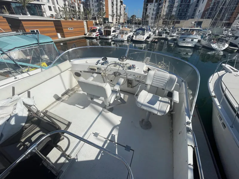 Slide: The Image of 1975 Uniflite Aft Cabin in marina, featuring helm and seating area. - 6