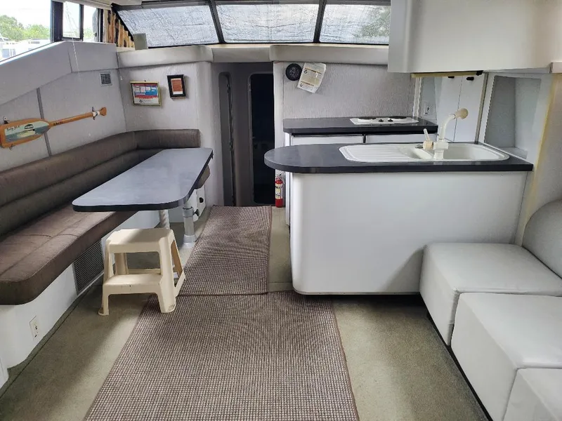 Slide: The Image of 1990 Mainship Mediterranean yacht interior with dining area, kitchenette, and modern seating. - 8