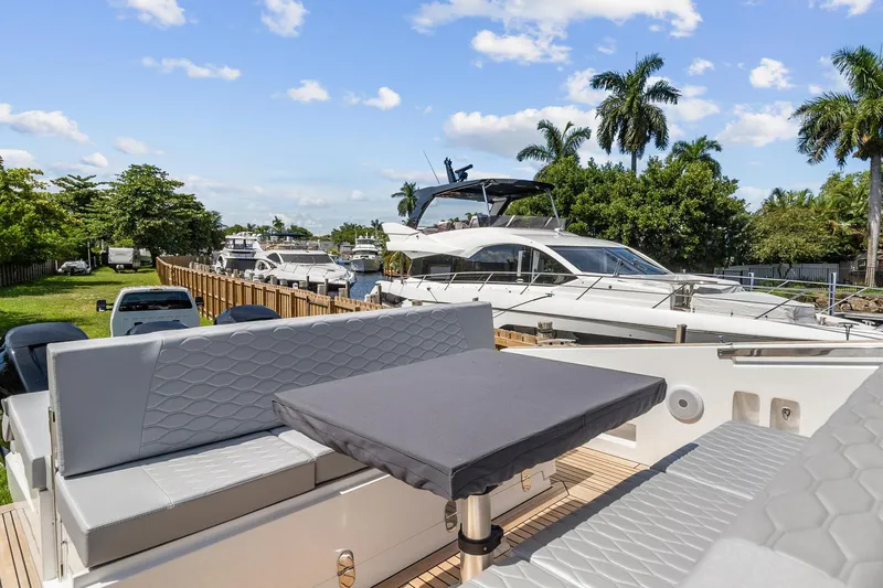 Slide: The Image of 2023 Astondoa 377 Coupe Outboard yacht with luxurious seating and table, docked near other boats. - 20