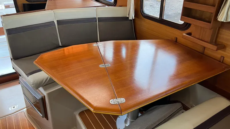 Slide: The Image of 2014 Ranger Tugs R29S interior dining area with wooden table and cushioned seating. - 12